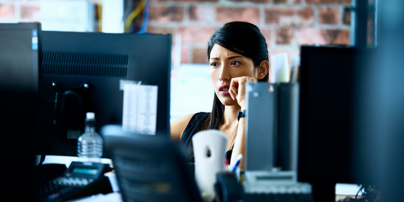 Image of a woman working at a computer while seated at a desk.