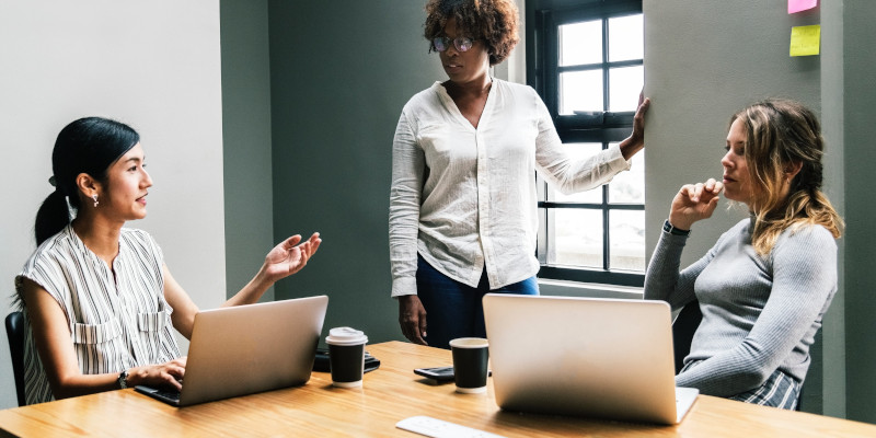 Three teammates are pictured brainstorming around a table.